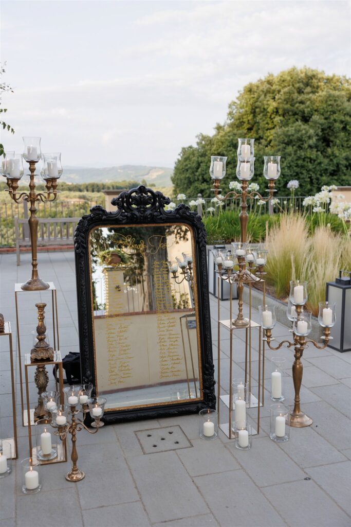 An Unforgettable Anniversary at Castello del Nero: A Three-Day Celebration in Tuscany 29 Elegant wedding seating chart reflected in ornate mirror with ornate candelabras. Anniversary Castello del Nero - Italian Wedding Designer