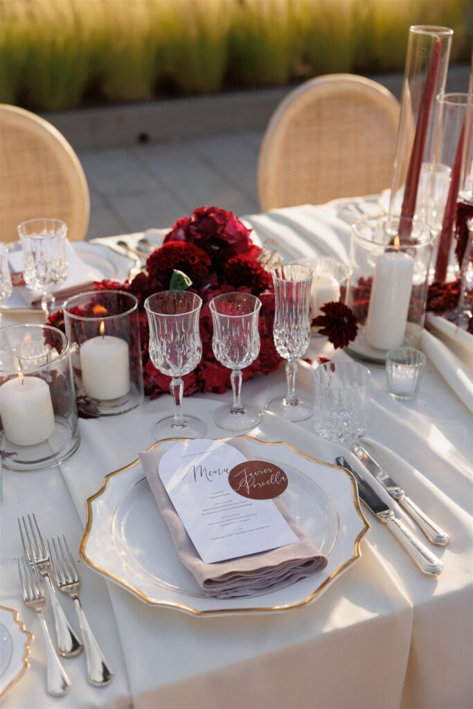 An Unforgettable Anniversary at Castello del Nero: A Three-Day Celebration in Tuscany 34 Elegant wedding table setting with red floral centerpiece, candles, and place cards. Anniversary Castello del Nero - Italian Wedding Designer
