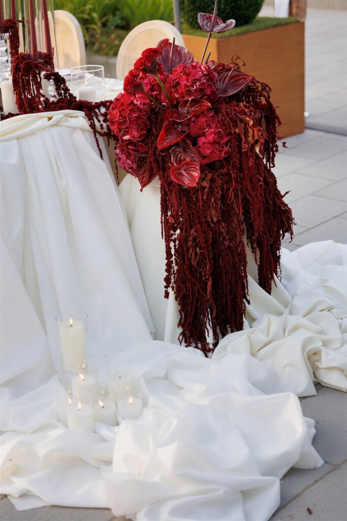 An Unforgettable Anniversary at Castello del Nero: A Three-Day Celebration in Tuscany 35 Dramatic red floral arrangement with cascading greenery and candles on a draped white table. Anniversary at Castello del Nero - Italian Wedding DesignerAnniversary Castello del Nero - Italian Wedding Designer