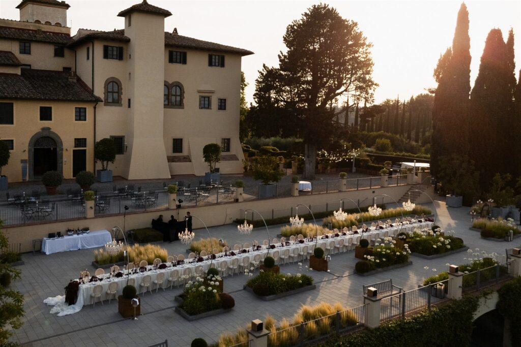An Unforgettable Anniversary at Castello del Nero: A Three-Day Celebration in Tuscany 41 Elegant outdoor wedding reception with long table set for guests at sunset. Anniversary Castello at del Nero - Italian Wedding Designer