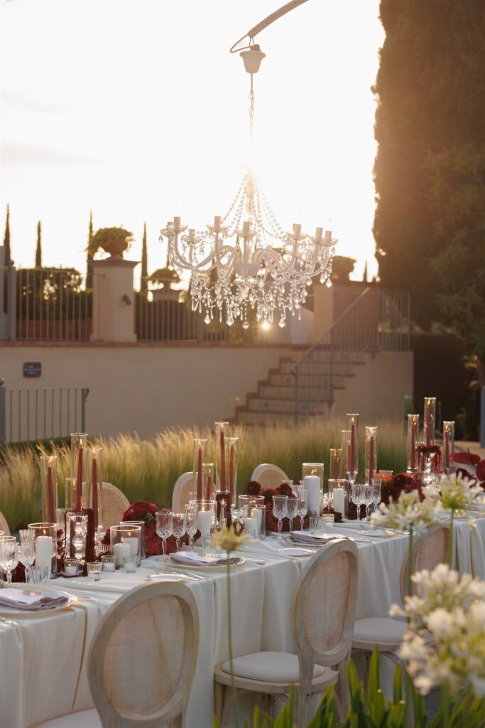 An Unforgettable Anniversary at Castello del Nero: A Three-Day Celebration in Tuscany 43 Elegant outdoor wedding reception table setting with chandelier and sunset glow. Anniversary at Castello del Nero - Italian Wedding Designer