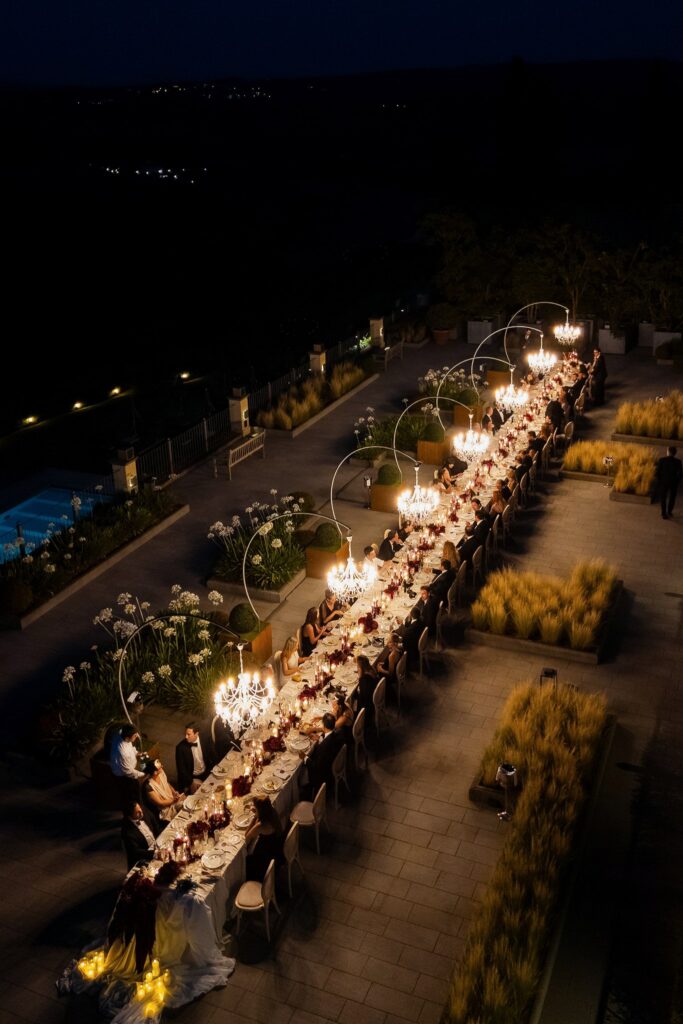 An Unforgettable Anniversary at Castello del Nero: A Three-Day Celebration in Tuscany 45 Elegant outdoor long table dinner party at night with chandeliers and guests. Anniversary at Castello del Nero - Italian Wedding Designer