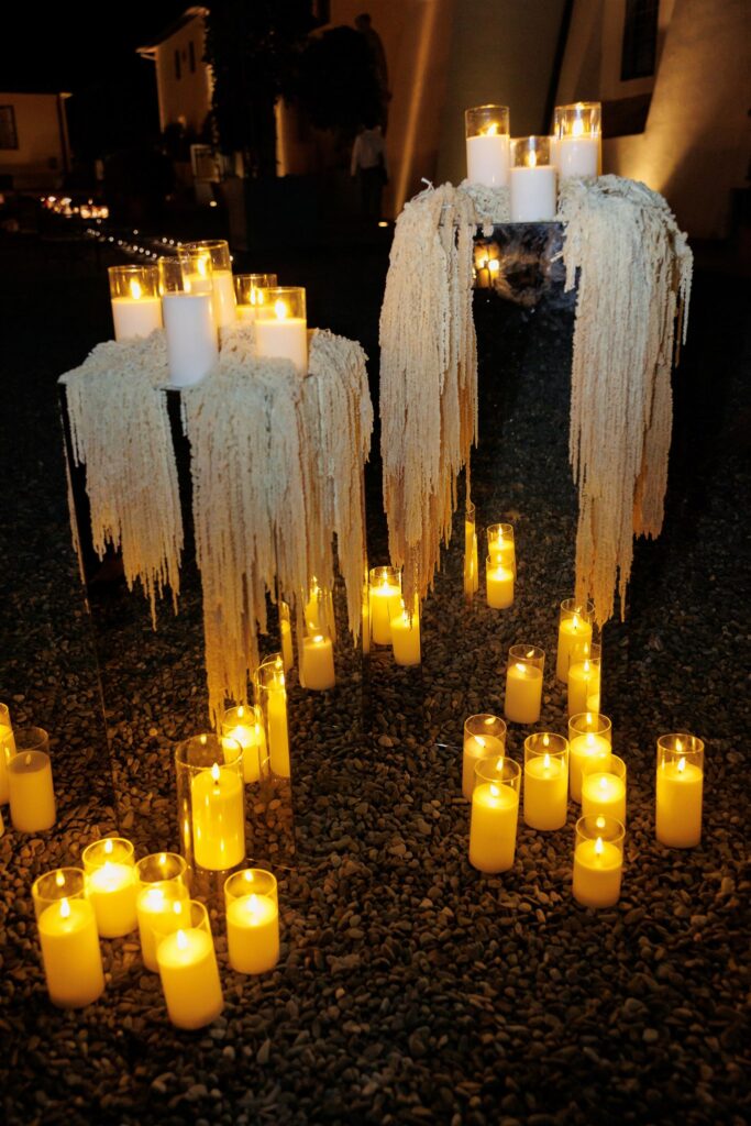 An Unforgettable Anniversary at Castello del Nero: A Three-Day Celebration in Tuscany 46 Candles lit at night on cobblestones, with draped fabric and more candles on pedestals. Anniversary at Castello del Nero - Italian Wedding Designer