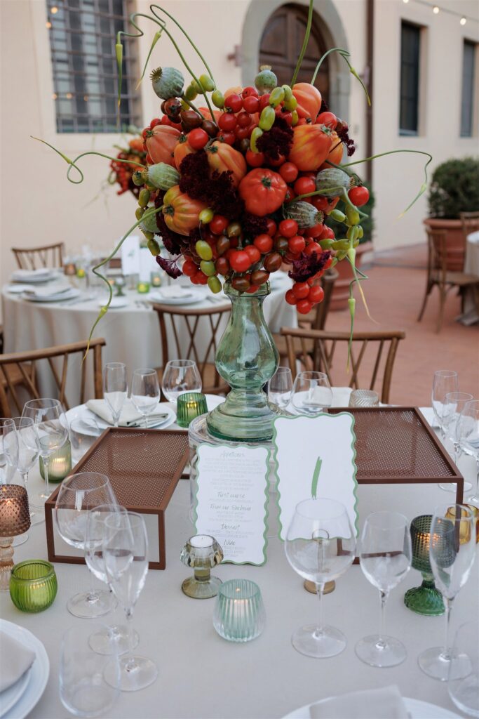 An Unforgettable Anniversary at Castello del Nero: A Three-Day Celebration in Tuscany 12 Vibrant fruit and vegetable centerpiece on a beautifully set outdoor wedding reception table.