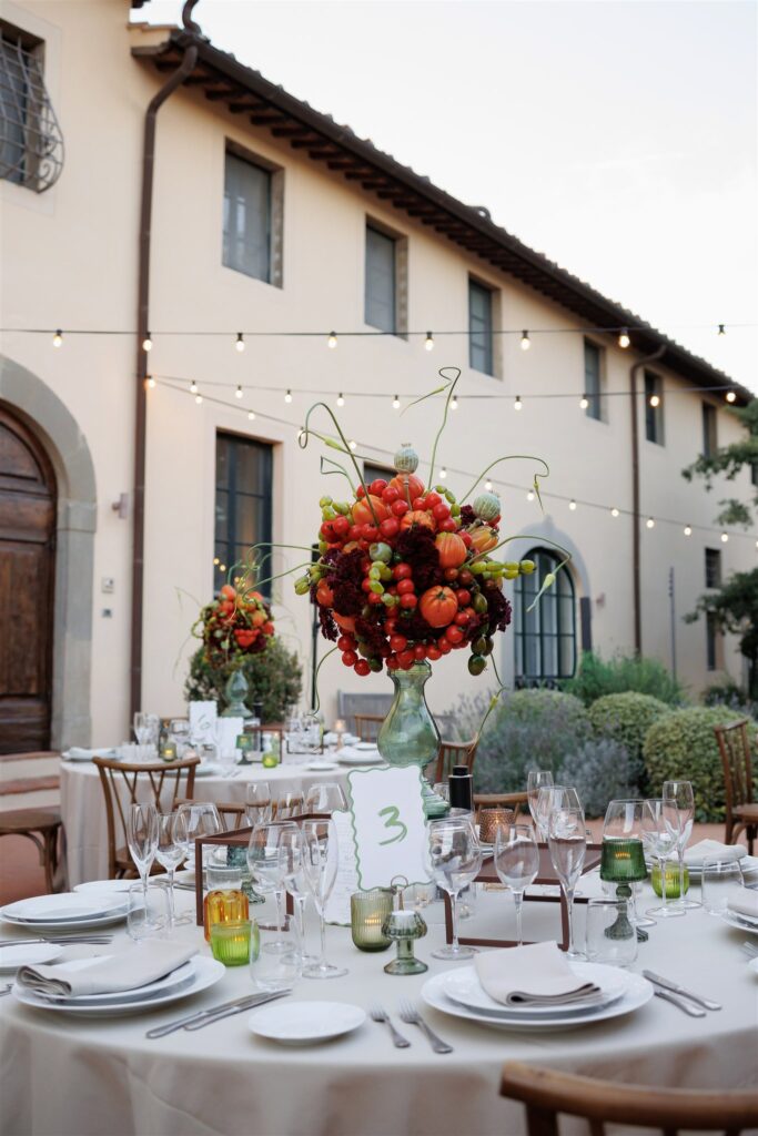 An Unforgettable Anniversary at Castello del Nero: A Three-Day Celebration in Tuscany 13 Elegant outdoor wedding reception table setting with floral centerpiece and string lights. Anniversary Castello del Nero - Italian Wedding Designer