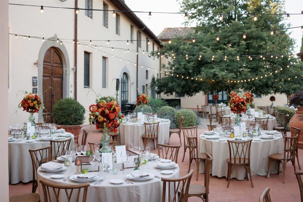 An Unforgettable Anniversary at Castello del Nero: A Three-Day Celebration in Tuscany 14 Elegant outdoor reception tables with floral arrangements and string lights at a Tuscan venue. Anniversary Castello del Nero - Italian Wedding Designer