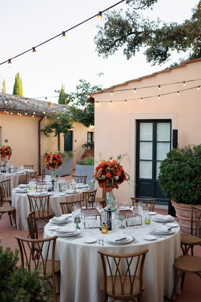 An Unforgettable Anniversary at Castello del Nero: A Three-Day Celebration in Tuscany 15 Outdoor Italian wedding reception with round tables, floral centerpieces, and string lights. Anniversary Castello del Nero - Italian Wedding Designer