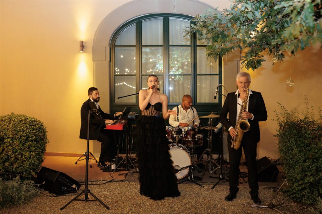 An Unforgettable Anniversary at Castello del Nero: A Three-Day Celebration in Tuscany 21 Live band with female singer, saxophonist, keyboardist, and drummer performing outdoors. Anniversary Castello del Nero - Italian Wedding Designer