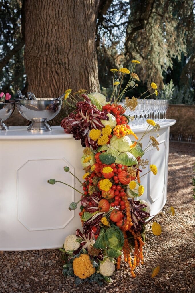 An Unforgettable Anniversary at Castello del Nero: A Three-Day Celebration in Tuscany 5 Edible floral arrangement of vegetables and fruits cascading down a white bar. Anniversary Castello del Nero - Italian Wedding Designer